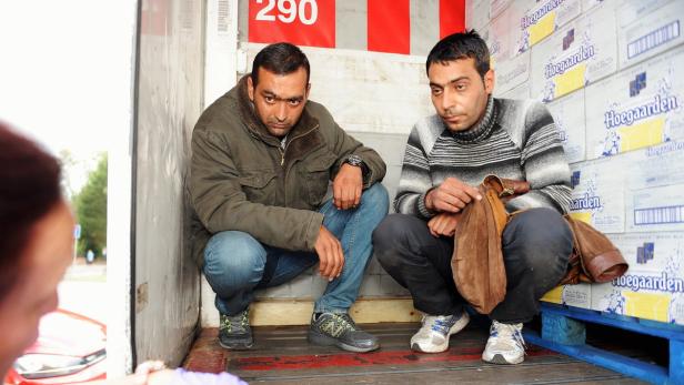 Zwei Männer hocken in einem Lieferwagen vor Kisten mit Hoegaarden-Bier.