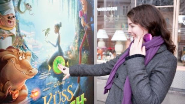 Eine Frau betrachtet das Filmplakat „Küss den Frosch“.