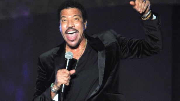 Lionel Richie singt mit erhobenem Zeigefinger auf der Bühne.