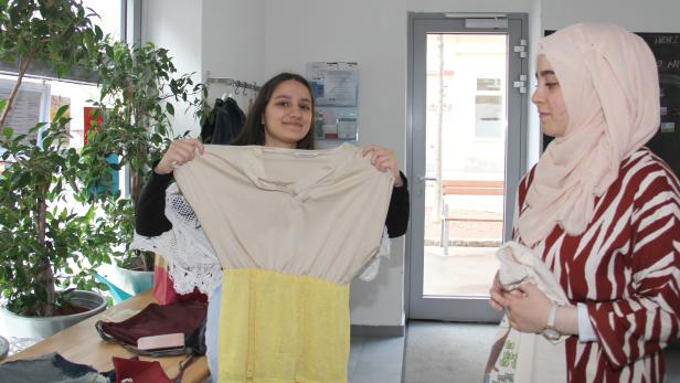 Balqiz und Israa ziegen dem Reporter verschiedene selbstgenähte Kleidungsstücke