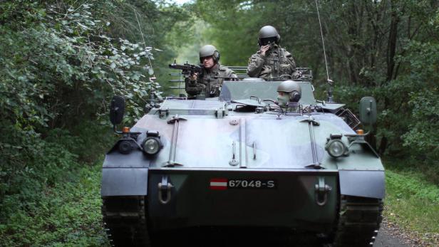 Soldaten in einem Schützenpanzer auf einer Waldstraße.