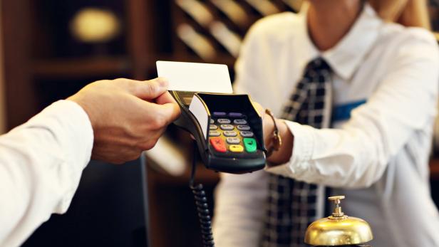 Ein Gast bezahlt mit einer Kreditkarte an der Rezeption eines Hotels.