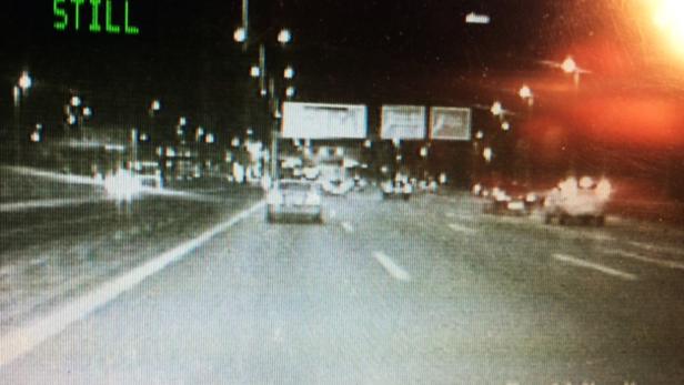 Eine nächtliche Aufnahme einer Autobahn mit fahrenden Autos.