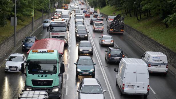 Stau auf einer regnerischen Straße mit vielen Autos und Lastwagen.