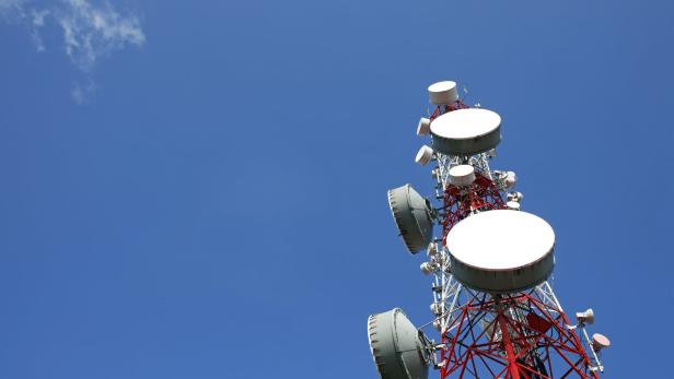 Ein rot-weißer Sendemast steht vor einem blauen Himmel.