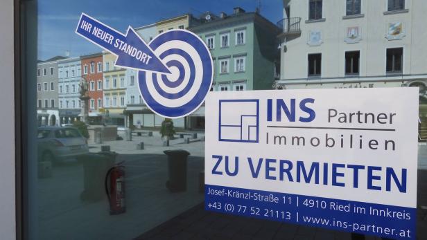 Ein Schaufenster mit Werbung für INS Partner Immobilien in Ried im Innkreis.