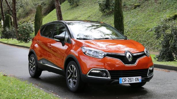 Ein orangefarbener Renault Captur steht auf einer Straße.