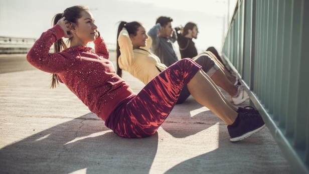 Eine Gruppe von Menschen macht Sit-ups im Freien.