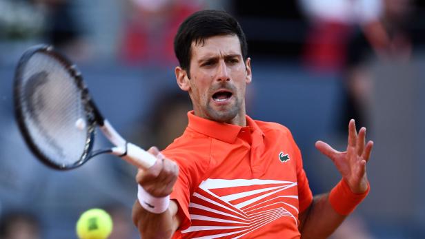 Novak Đoković beim Tennisspiel in einem orangefarbenen Hemd.