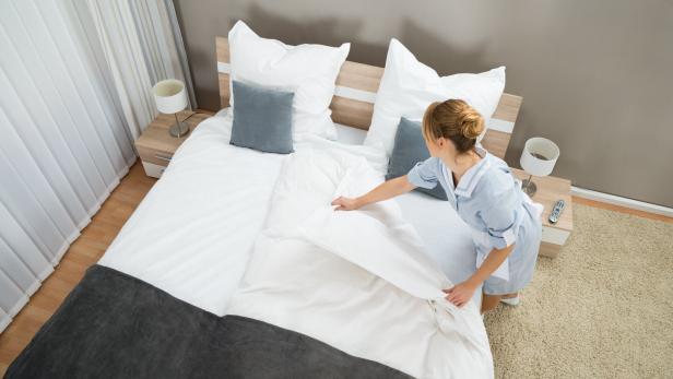 Eine Mitarbeiterin bereitet ein Hotelzimmer vor. 
