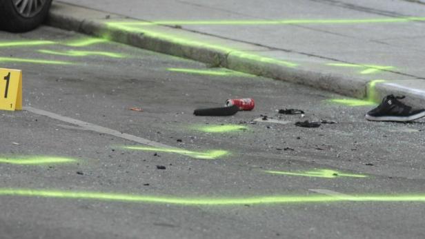 Eine Unfallstelle auf der Straße mit Markierungen, einer Dose und einem Schuh.