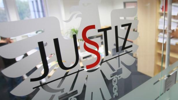 Das Logo der Justiz mit dem Bundesadler auf einer Glastür.