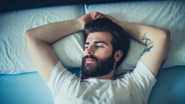 Portrait of sad bearded man lying down in the bad
