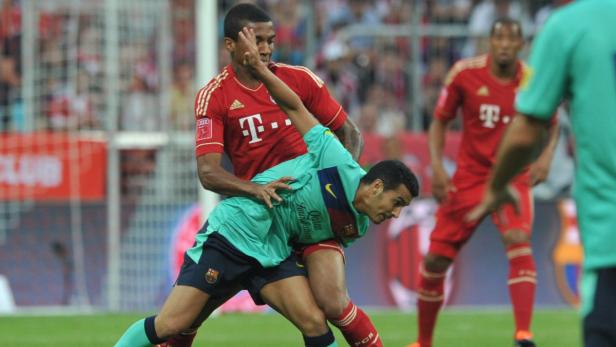 Ein Fußballspieler im roten Trikot foult einen Spieler im türkisfarbenen Trikot.