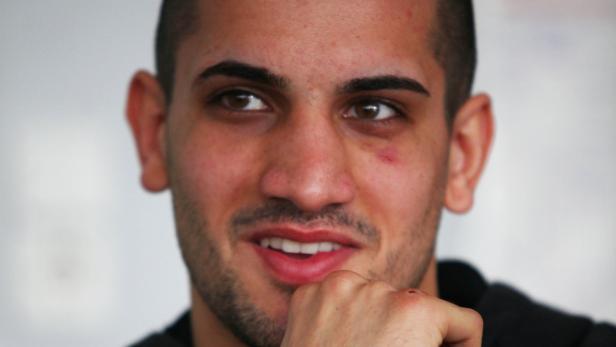 Ein junger Mann mit kurzem Haar lächelt und blickt zur Seite.