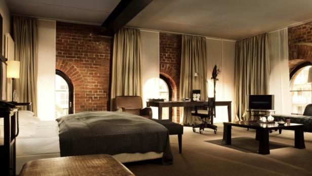 Ein Hotelzimmer mit freiliegendem Backstein, einem Bett und einem Schreibtisch.