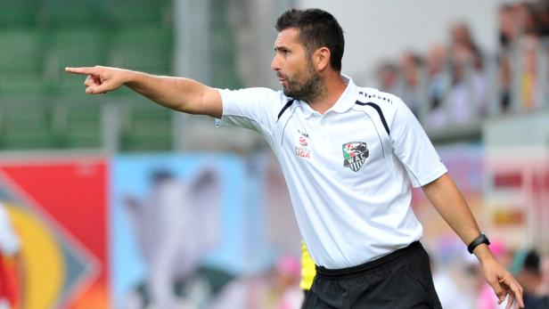 Ein Mann in Sportkleidung zeigt mit dem Finger nach links.