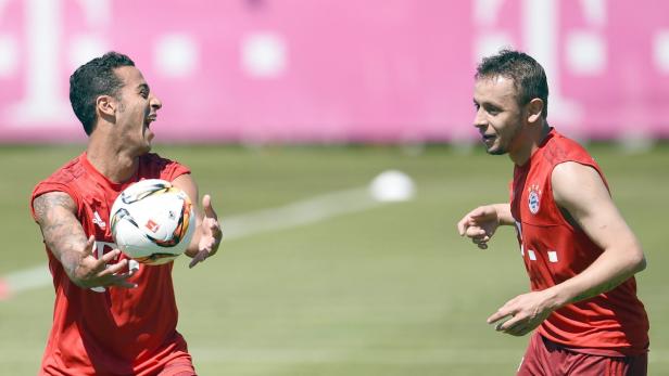 Zwei Fußballspieler des FC Bayern München trainieren mit einem Ball auf dem Rasen.
