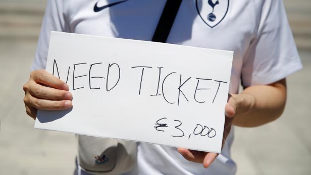 Eine Person im Tottenham Hotspur Trikot hält ein Schild mit der Aufschrift „Need Ticket €3,000“.
