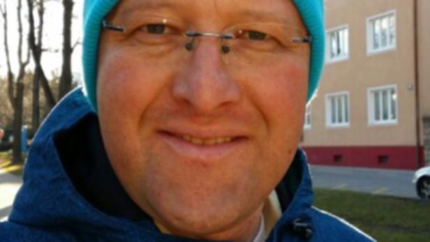 Ein Mann mit Brille und blauer Mütze lächelt in die Kamera.