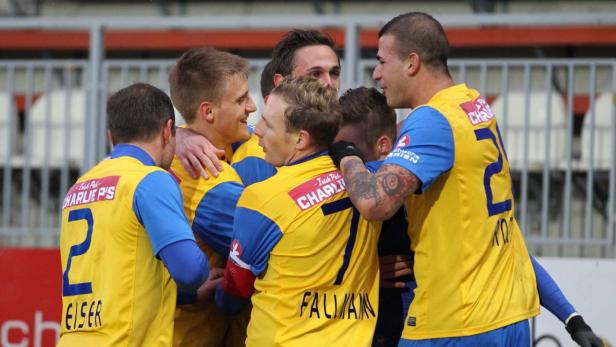 Eine Gruppe von Fußballspielern in gelb-blauen Trikots umarmt sich auf dem Spielfeld.