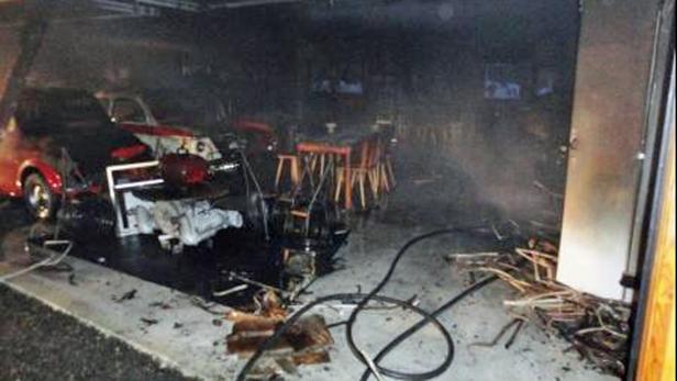 Ein durch einen Brand beschädigter Garageninnenraum mit einem Auto und Möbeln.