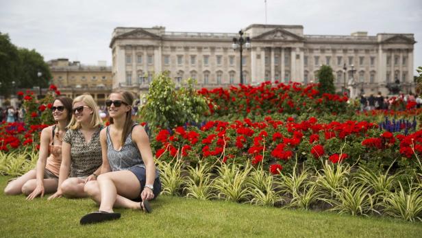 Touristen posieren vor dem Buckingham Palace in London.