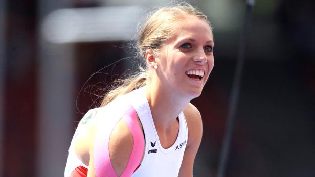 Eine lächelnde, blonde Sportlerin mit Kinesio-Tape am Arm trägt ein Trikot mit der Aufschrift „Austria“.