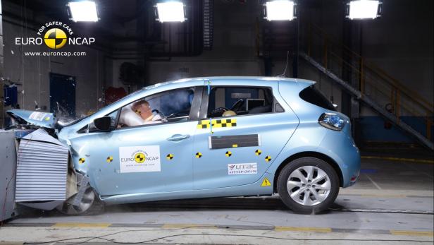 Ein hellblaues Auto bei einem Crashtest mit einer Dummypuppe im Fahrersitz.