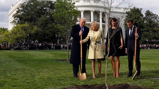 Brigitte Macron holds the shovel used by U.S. President Donald Trump after a tree planting as and first lady Melania Trump and French President Emmanuel Macron stand on the South Lawn of the White House in Washington