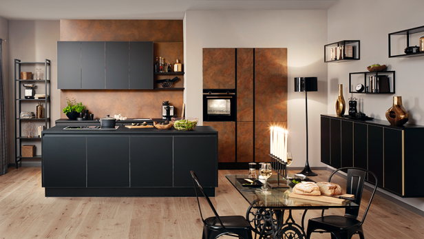 Moderne Küche mit dunklen Schränken, Kochinsel, Esstisch mit Brot und Kerzen sowie dekorativen Elementen an den Wänden.