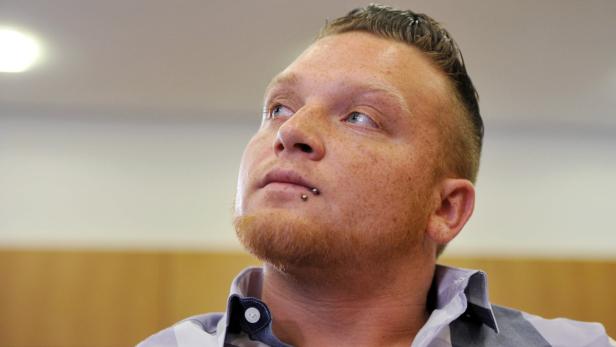 Ein Mann mit Bart und Lippenpiercing blickt nach oben.