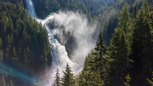 Ein hoher Wasserfall stürzt inmitten eines dichten Waldes herab.
