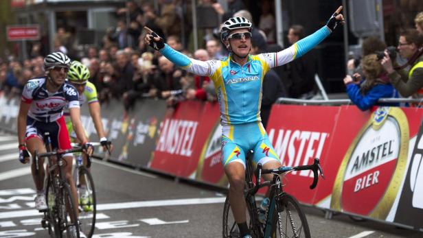 Ein Radrennfahrer überquert mit erhobenen Armen die Ziellinie.