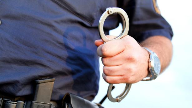 Ein Polizist hält Handschellen in der Hand.