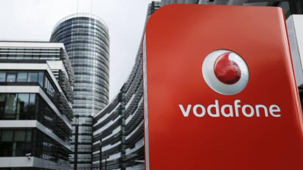 Ein rotes Vodafone-Logo vor modernen Bürogebäuden.