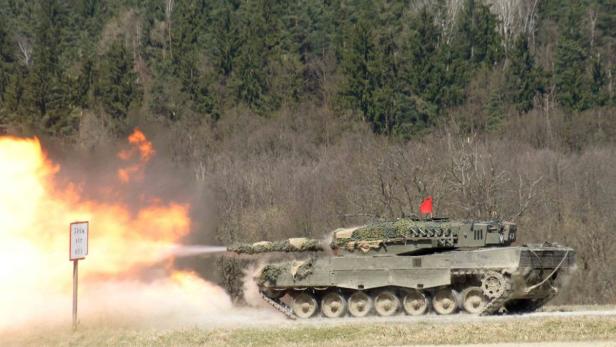 Ein Leopard-2-Panzer feuert mit einer großen Stichflamme auf einem Übungsplatz.
