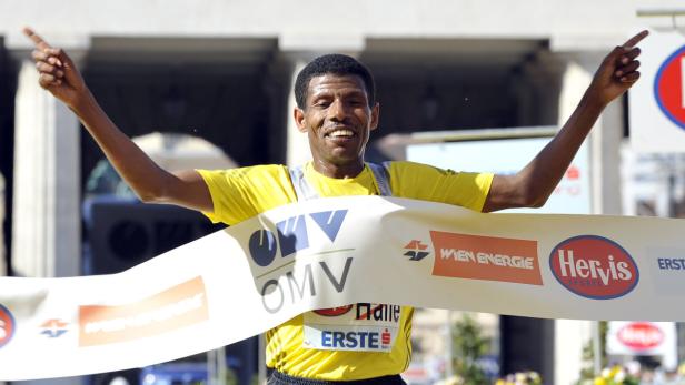 Ein Marathonläufer überquert mit erhobenen Armen die Ziellinie.