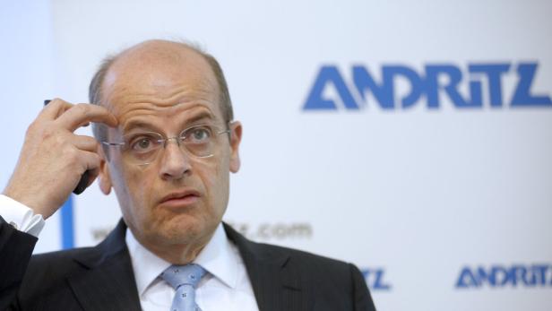 Ein Mann mit Brille gestikuliert vor einem Andritz-Logo.