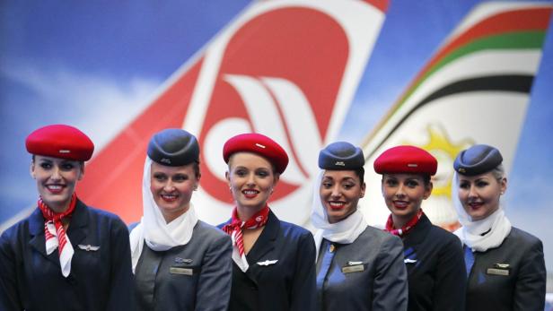 Eine Gruppe Stewardessen posiert vor Flugzeugleitwerken verschiedener Fluggesellschaften.