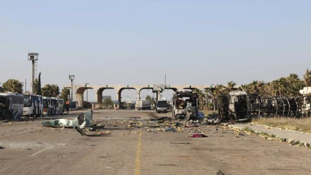 Zerstörte Busse und Trümmer blockieren eine Straße vor einem Grenzübergang.