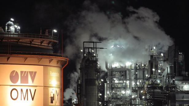 Eine OMV-Raststätte in Gänserndorf bei Nacht mit einer Ölraffinerie im Hintergrund.