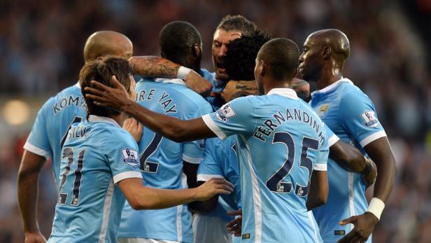 Eine Gruppe Fußballspieler in hellblauen Trikots umarmt sich auf dem Spielfeld.