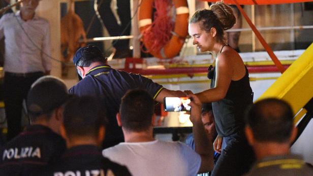 Carola Rackete, the 31-year-old Sea-Watch 3 captain, is escorted off the ship by police and taken away for questioning, in Lampedusa