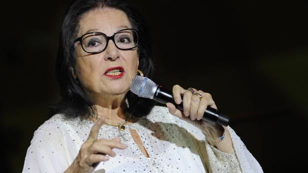Eine Frau mit Brille singt in ein Mikrofon.