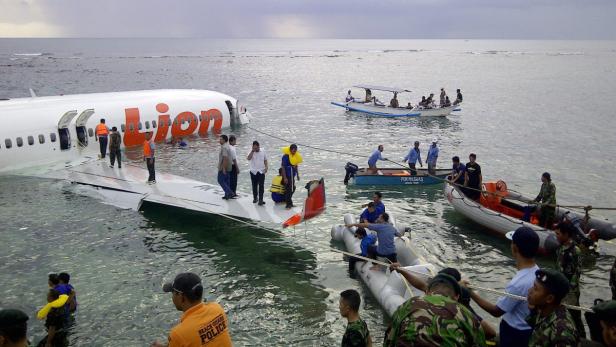 Ein Lion Air Flugzeug liegt nach einer Notwasserung im flachen Wasser vor der Küste.