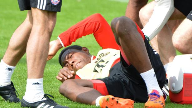 Ein Fußballspieler liegt erschöpft auf dem Rasen, umgeben von anderen Spielern.