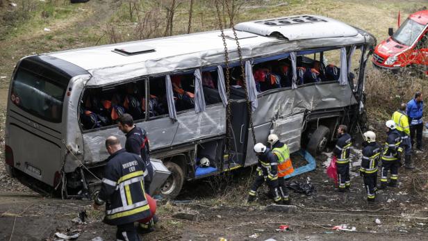 Ein schwer beschädigter Bus nach einem Unfall wird von Rettungskräften untersucht.
