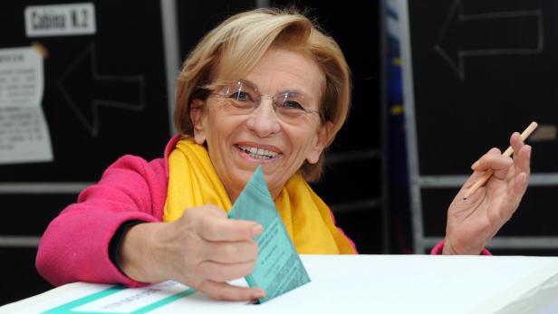 Eine Frau wirft einen Stimmzettel in eine Wahlurne.