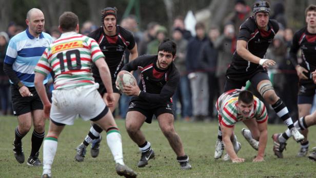 Rugbyspieler kämpfen um den Ball auf einem schlammigen Feld.